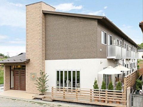 周りにグリーンを配置したツートーンカラーの建物