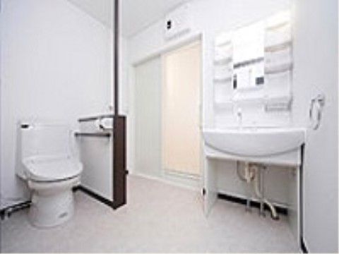壁に手すりが設置され、入り口横に洗面台を完備したトイレ