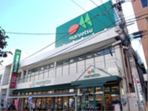 建物の上に大きな緑色の看板が設置されているスーパーの外観