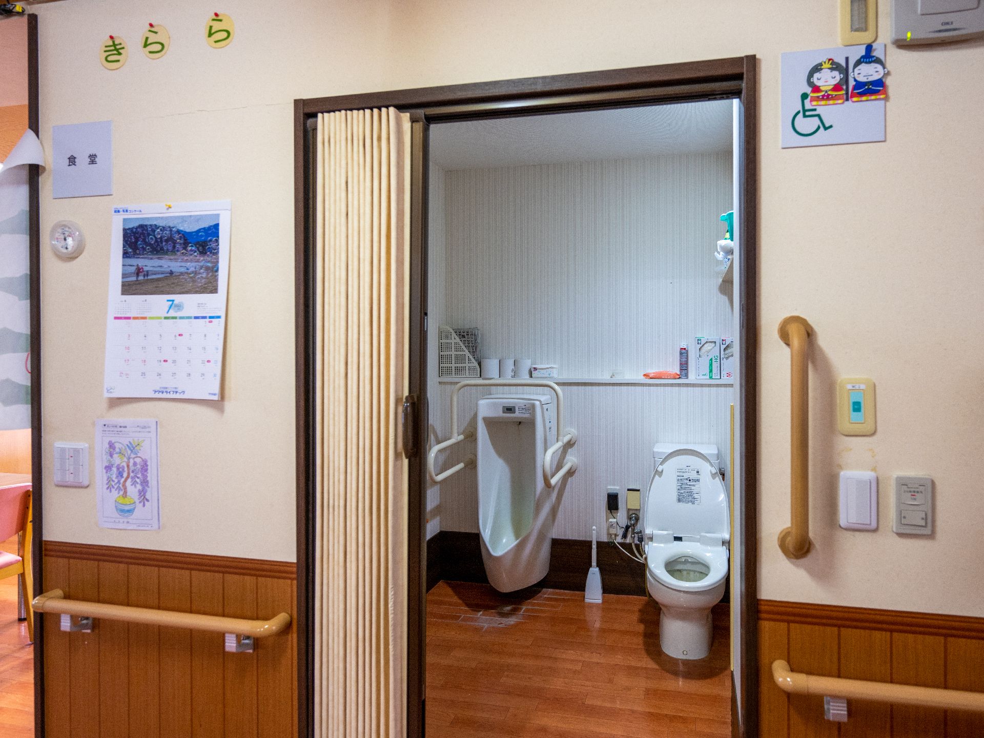 スライド式の扉の先にある小便器と洋式便器が置かれたトイレ