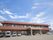 ブラウン系の2階建ての建物。2階部分にはベランダが付き、玄関には車寄せがあり、駐車場も用意されている。