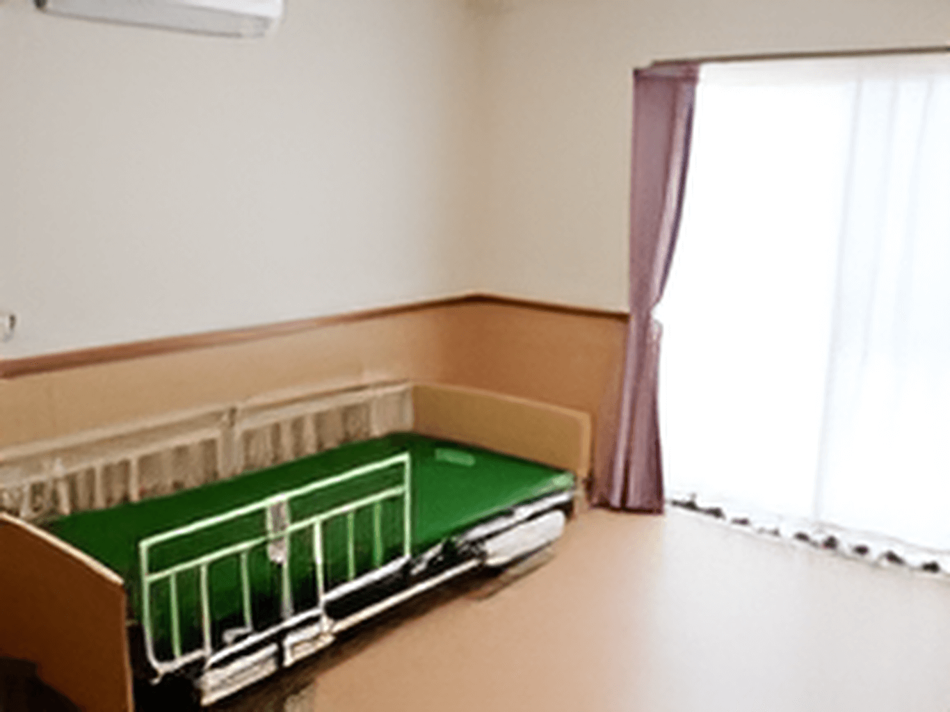 転倒防止用の柵が付いたベッドが置かれたフローリングの居室。