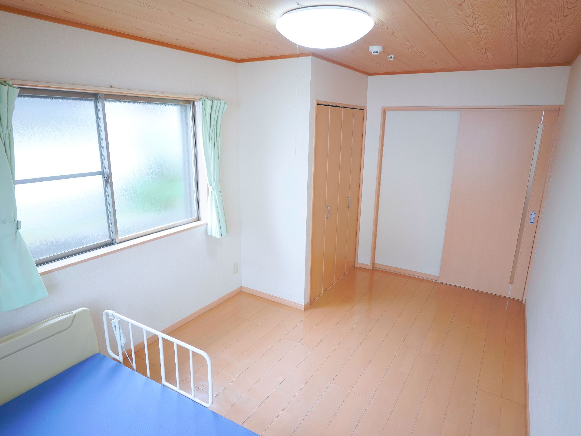 鏡を見ながら笑顔で話している高齢者とそこに寄り添介護スタッフの様子。明るい室内の写真