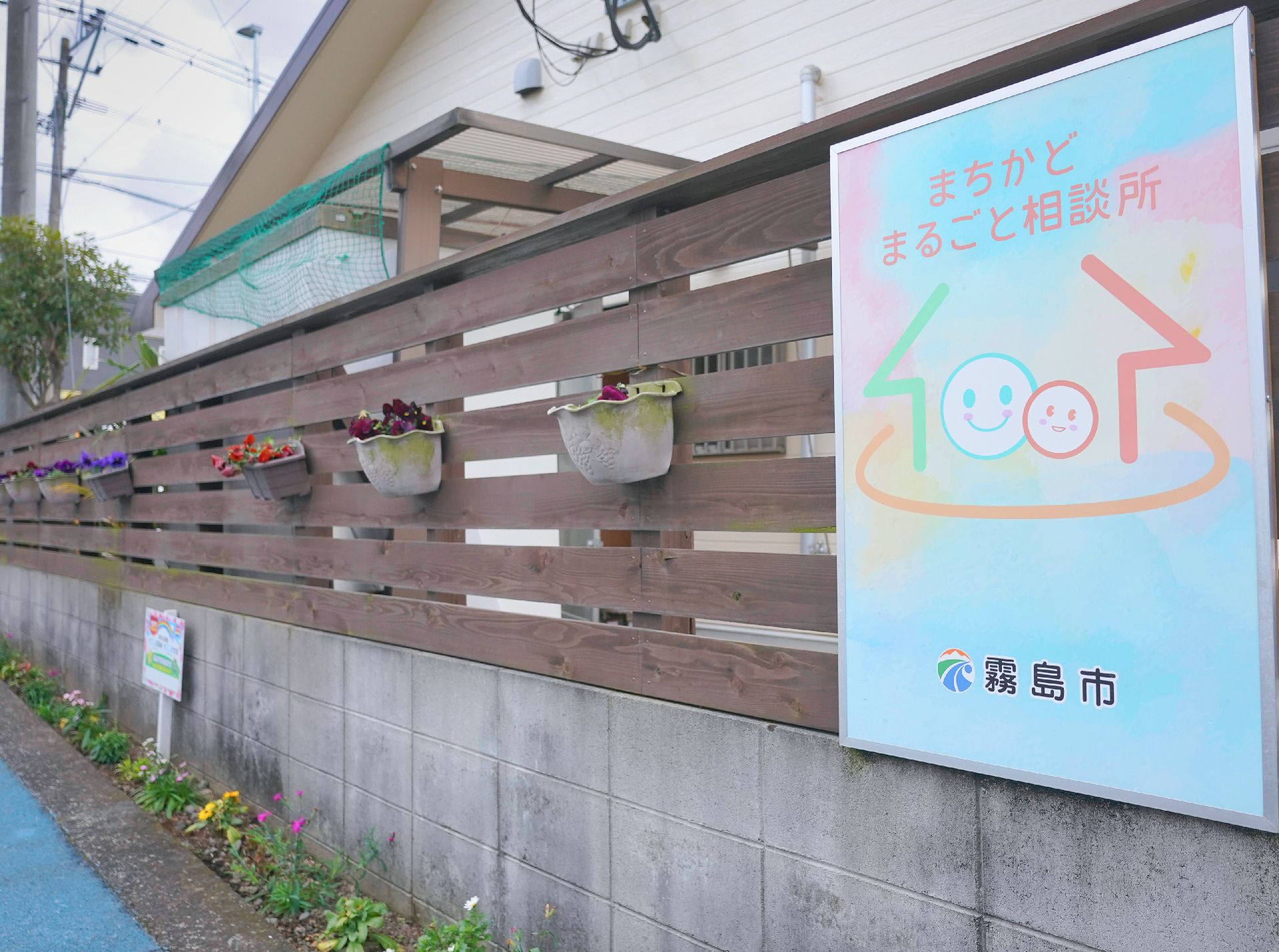 こちらを向いて笑顔になる車いすの高齢女性と介護施設の女性スタッフの様子