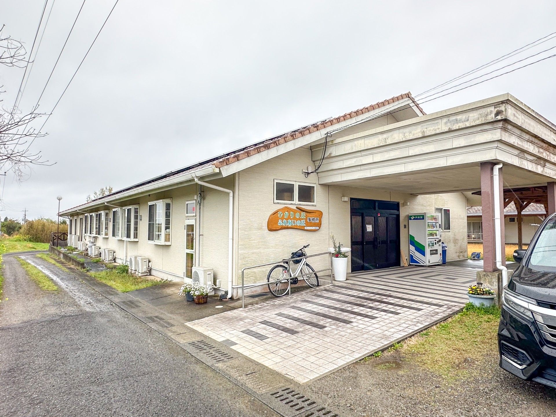 エプロンを付けた若い女性スタッフとカーディガンを着た車いすの高齢女性が笑顔で話している。