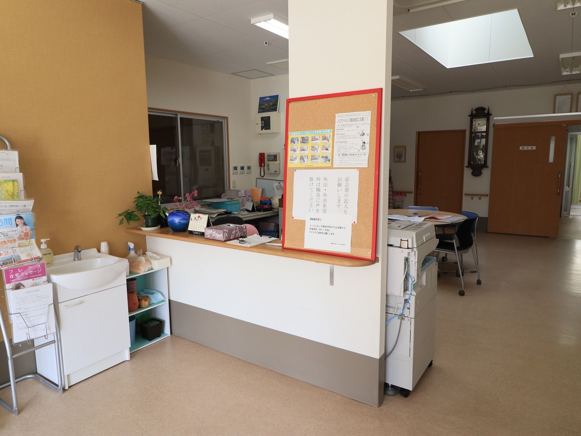カウンターがあり、向こうにスタッフの事務作業スペースがある。カウンターには掲示板があり、隣には洗面台がある。