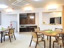 正面にシステムキッチンが付いた食堂には4人掛けのテーブルが複数置かれている。