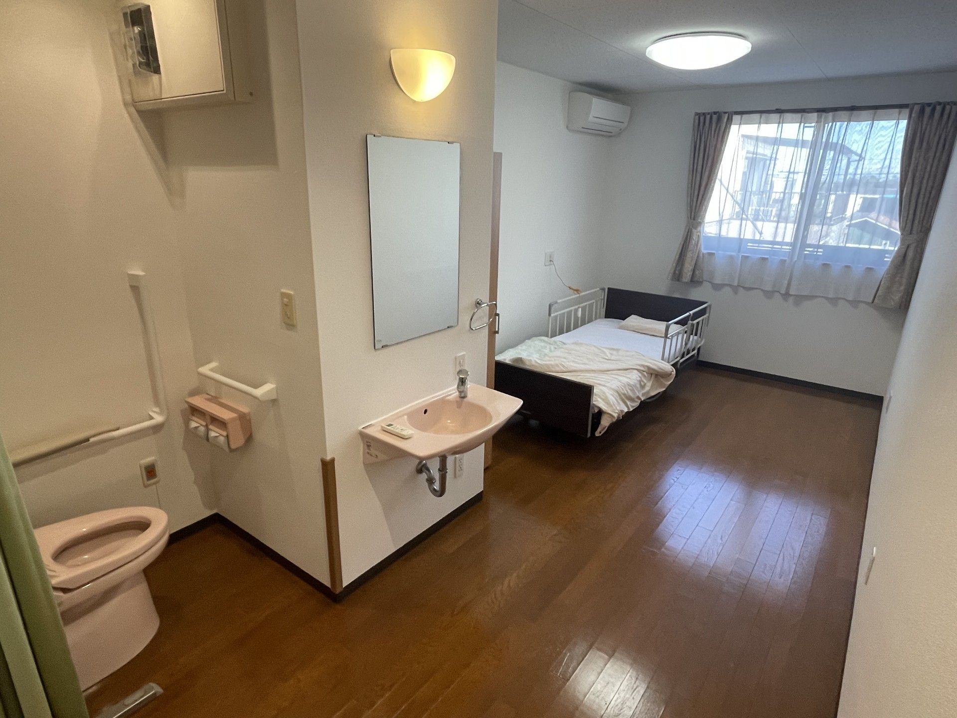 薄ピンク色をしたトイレと洗面台がある居室