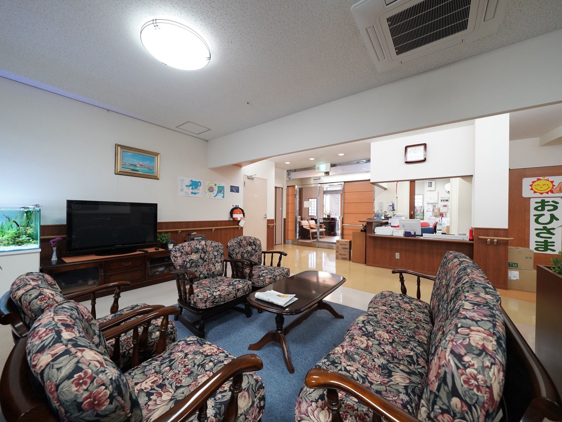 こげ茶色のテーブルを囲むように、シックな花柄のソファーが設置されている。大きなテレビの横には、アクアリウムが飾ってある。