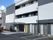 白とグレーのすっきりとした印象の建物。建物の玄関にはホームの名前が入っている。