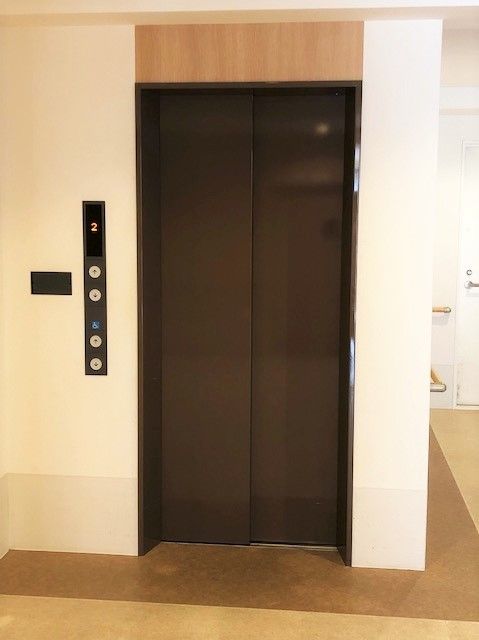 ブラウンのエレベーターの横には操作が簡単なシンプルなボタンが付いている。