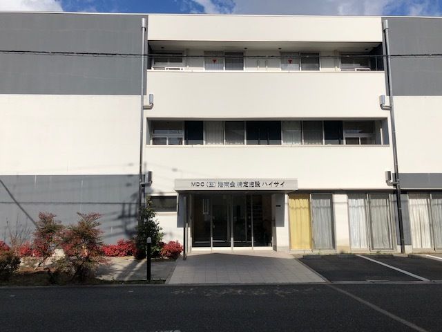 ３階建ての建物は横に長く、各フロアにバルコニーもついている。建物の前には木も植えられている。