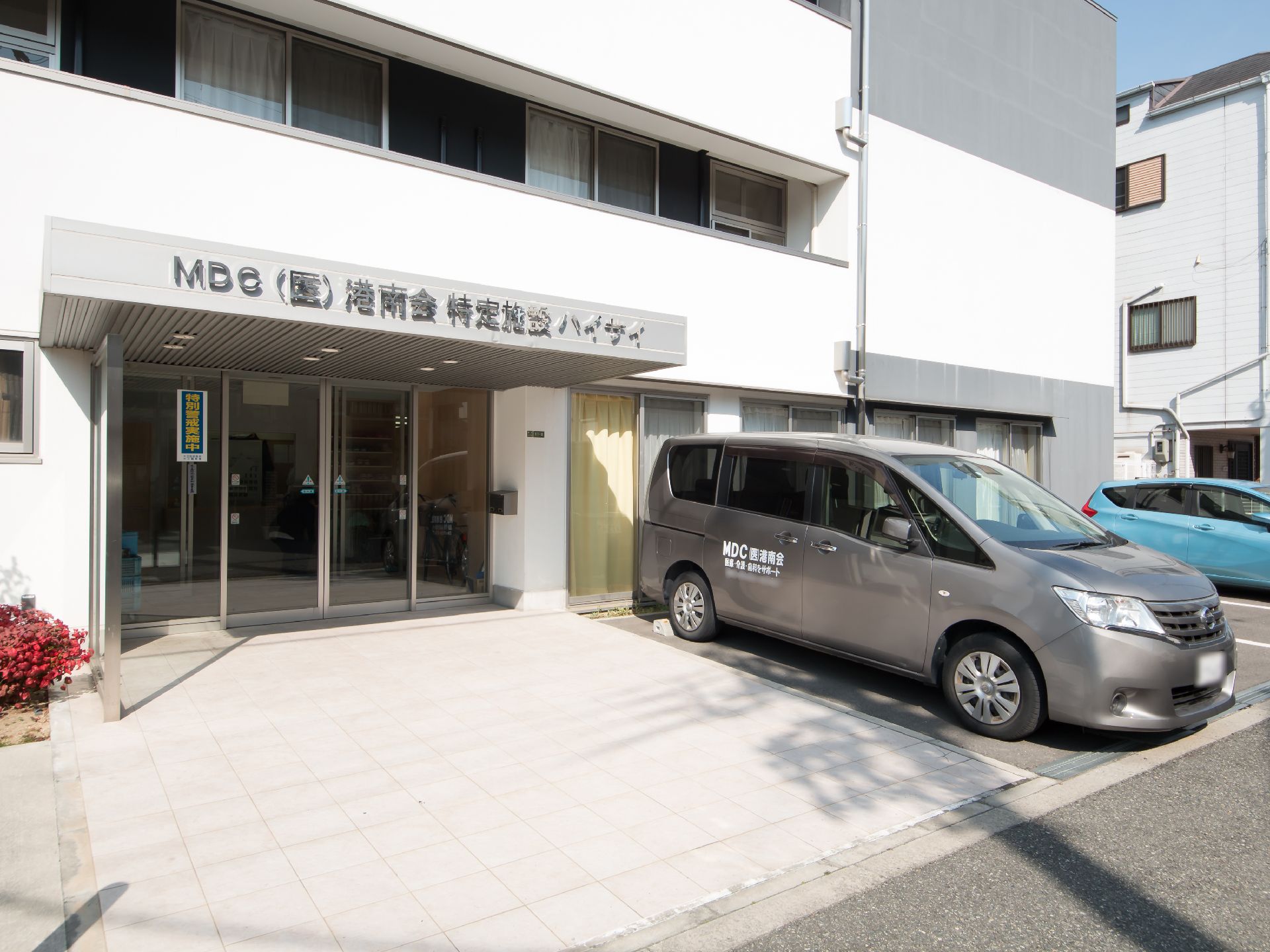 白とグレーを基調とした明るい雰囲気の外観。道路から入り口まで、段差のないバリアフリー仕様になっている。