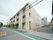 落ち着いた色合いに施された、3階建ての施設である。外壁に縦型の看板が設けられており、道路から目立ちやすい。