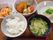 白いご飯に味噌汁、野菜の煮ものに揚げ物、冷ややっこなどが並べられ、手前には箸が置かれている。