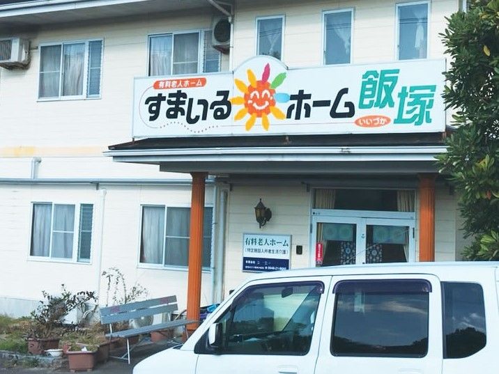 鉄骨造の建物の写真。「すまいるホーム飯塚」の看板が掲げてある