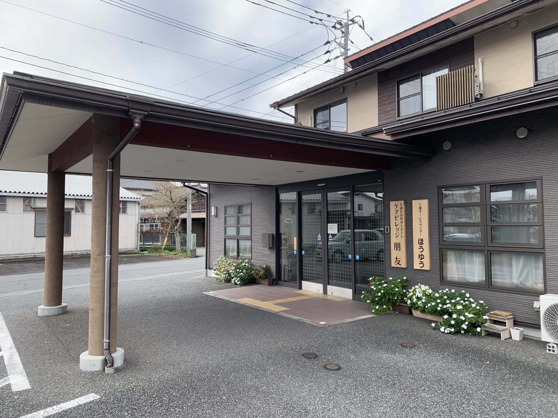 木陰にいる車椅子に座った高齢男性と介助をする女性ヘルパー
