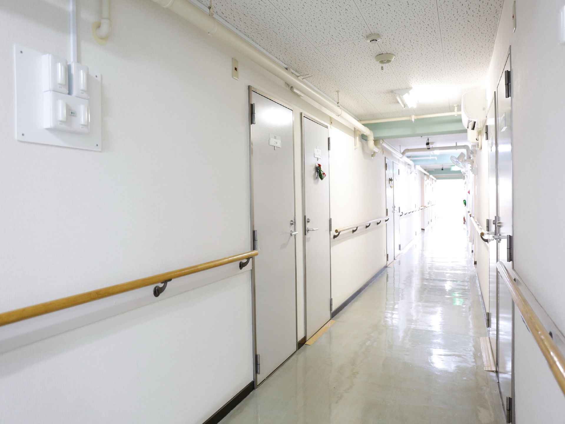 途切れなく手すりを設置してあり転倒防止に努めている。白い床と壁は清潔感がある。車いすが余裕をもって通れる幅。