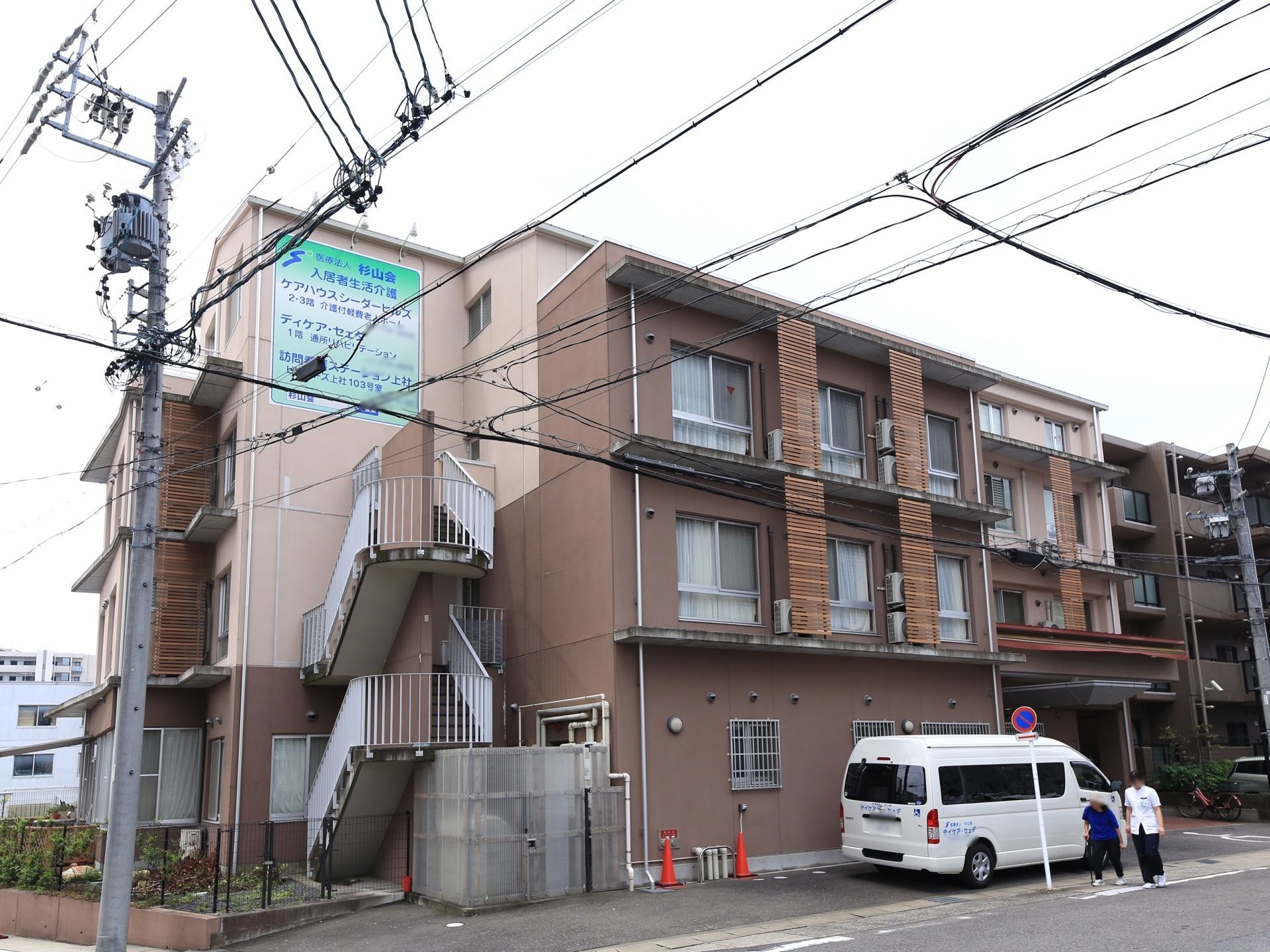 ３階建ての深いクリーム色が特徴の外観である。非常階段はらせん状になっており、駐車場も完備されている。