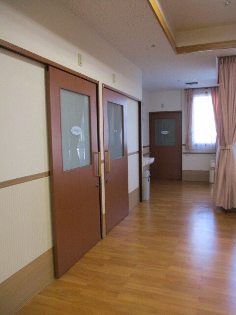 スライド式のドアが設置された居室が並んでいるまっすぐな廊下の突き当りには窓がある。