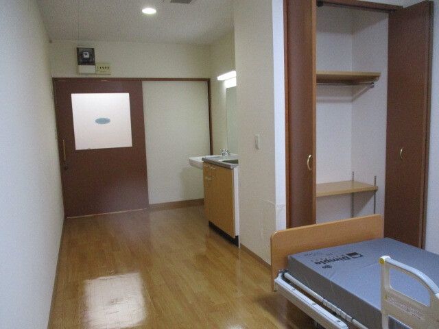クローゼットがや洗面所、ミニキッチン付きのフローリングの部屋には介護ベッドを置いている。