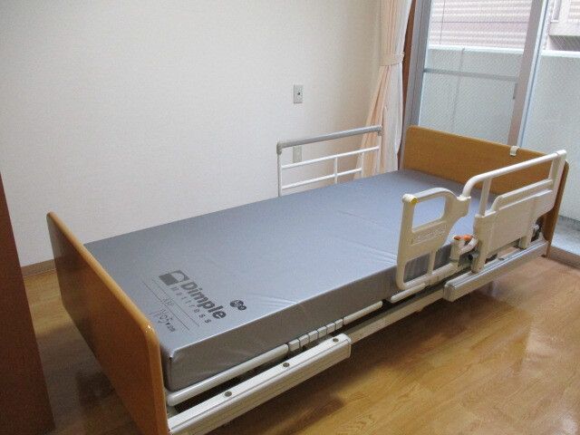 介護ベッドが置かれているフローリングの部屋には大きな窓があり、ベッドサイドには緊急通報装置がある。