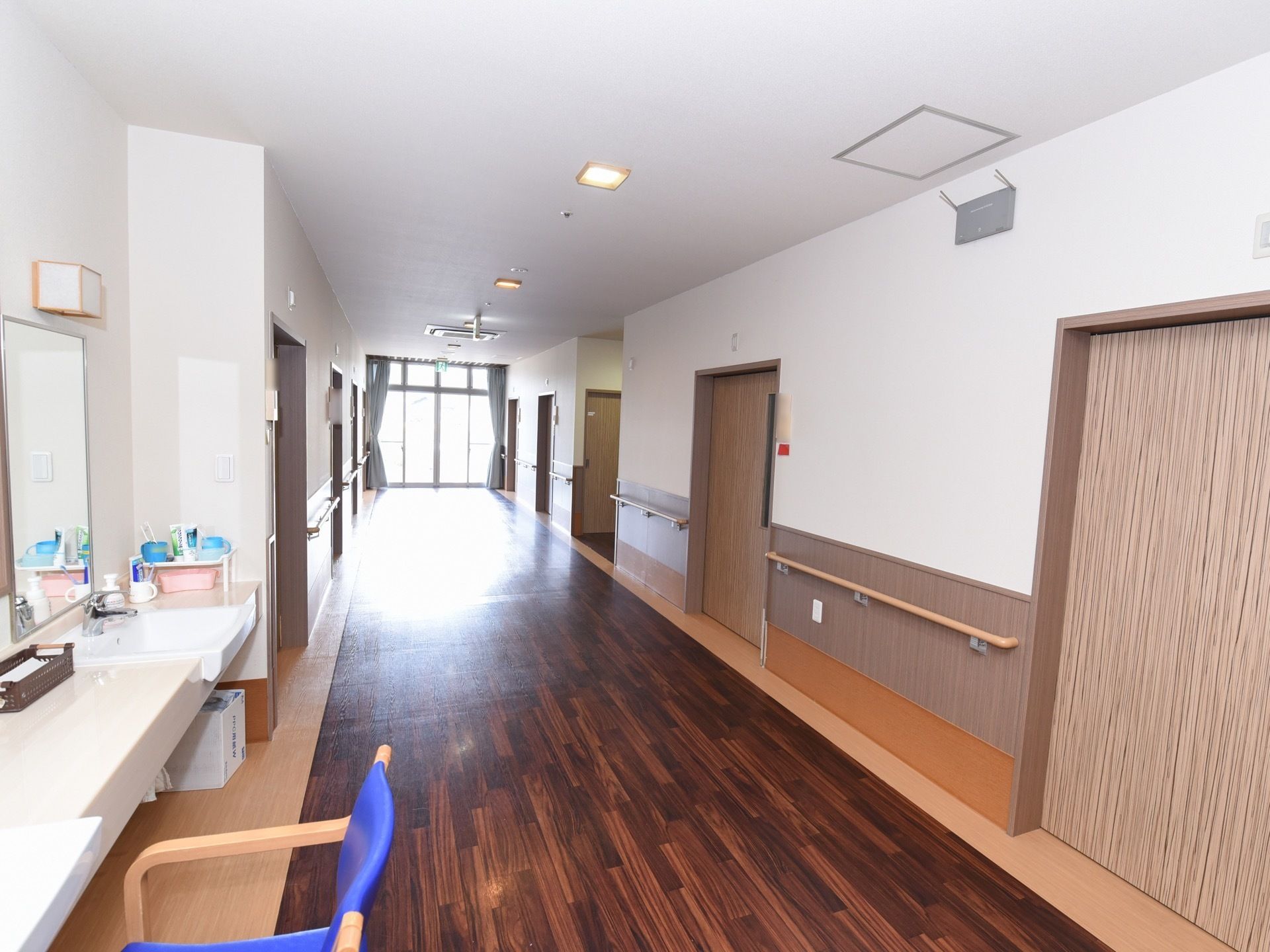 通路には部屋の扉が何枚かあり、壁には手すりが取りつけられている。扉の向かい側には洗面台が設置されている。