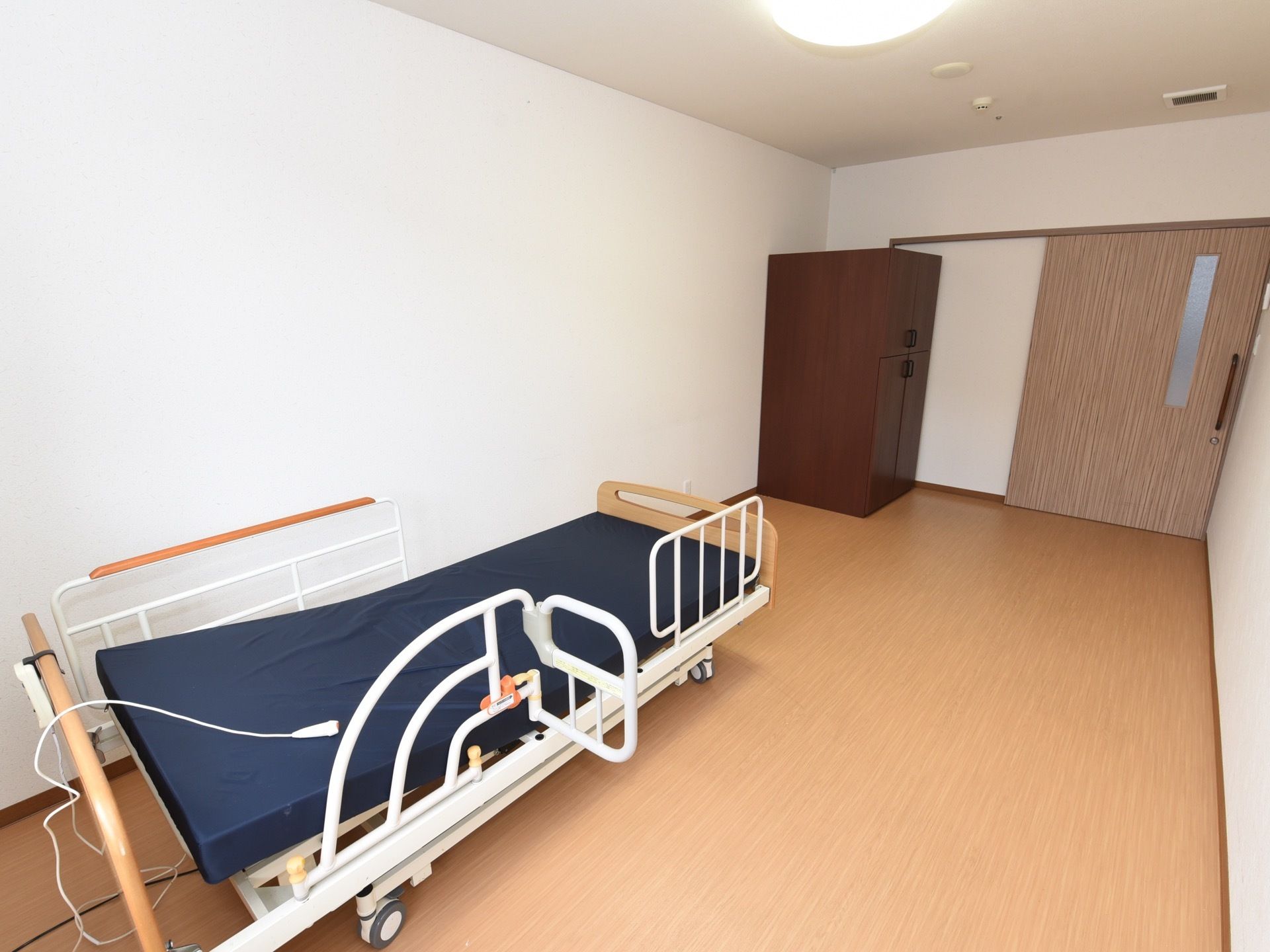 居室の扉はスライド式である。扉近くには木製のタンスが1竿置かれており、離れた場所にはベッドが1台ある。