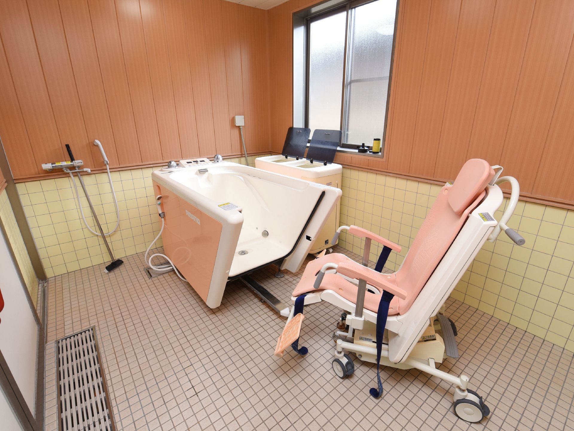 入浴用機器が設置され、前に移動できる付属の椅子が置いてある機械浴室