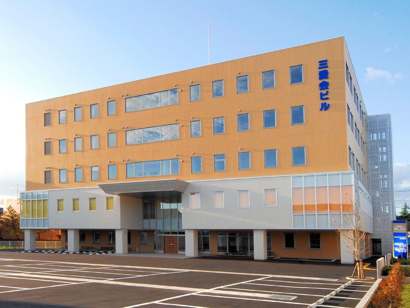 オレンジをメインとした外壁の大きな建物は横に長く、敷地内には駐車場があり、窓もたくさんついている。