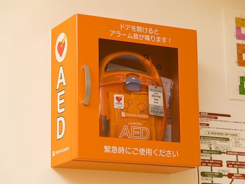 AEDと大きな文字で書かれたオレンジの箱の中にはAEDが入っている。「緊急時にご使用ください」とも書かれている。