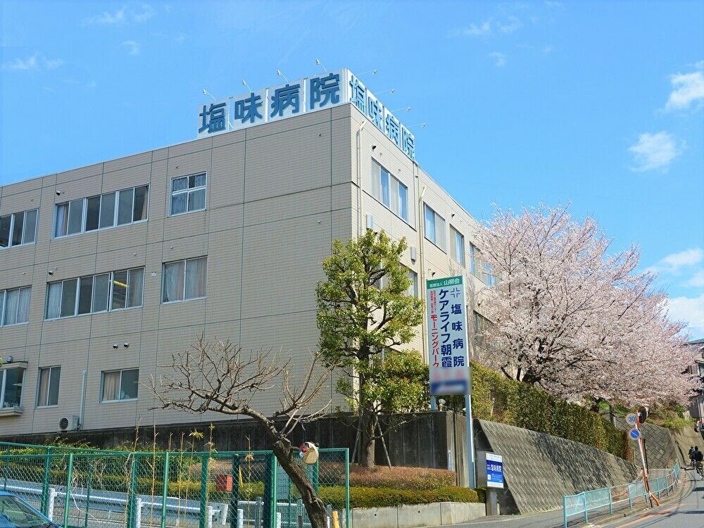 道路に面した３階建てで、塀の脇に看板を掲げている施設の外観