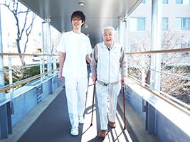 カメラに向かって笑顔を見せる車いすの女性とその家族、男女のスタッフの様子
