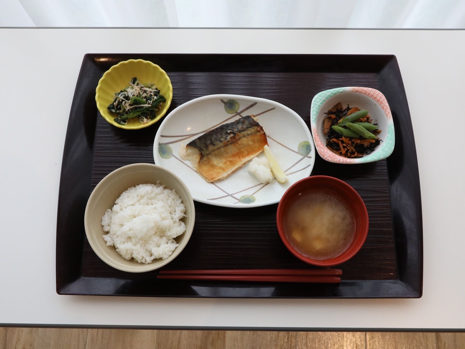さばの味噌煮、ほうれん草のしらす和え、ひじき煮、ご飯、味噌汁と、バランスのとれた食事が綺麗に盛り付けられている。