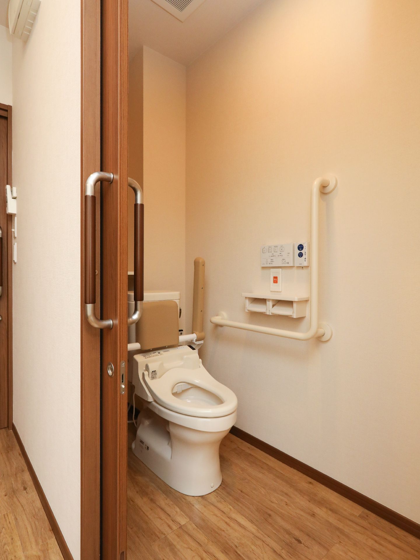 立ち上がり用と移動用の手すりが取り付けてある家庭サイズのトイレ。居室内の小さなタイプ
