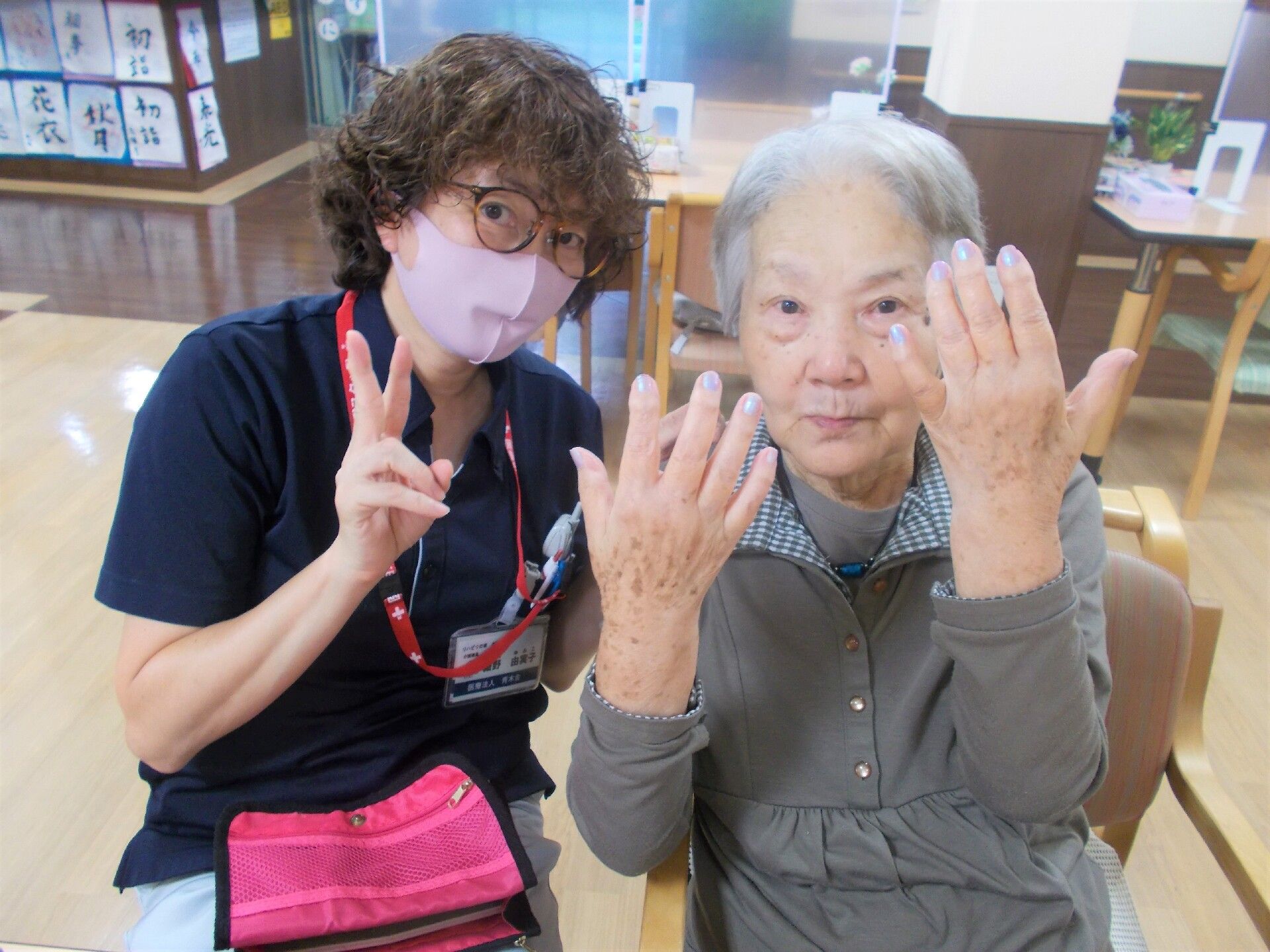 手をこちらに向けて写真に納まる高齢者と施設スタッフの様子