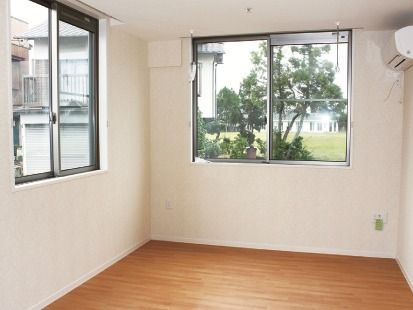 白い壁にフローリングの床。居室にはエアコンが設置されている。