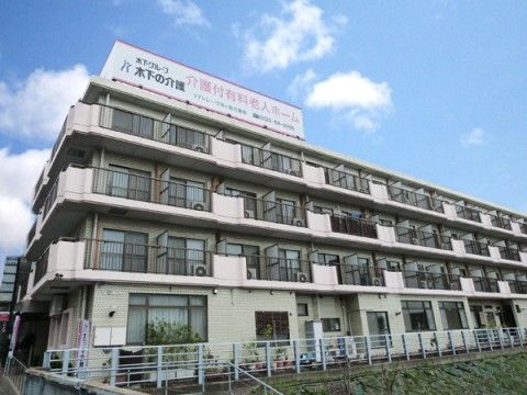 施設名が書かれた大きな看板が屋根の上に設置されている、3階建ての施設建物