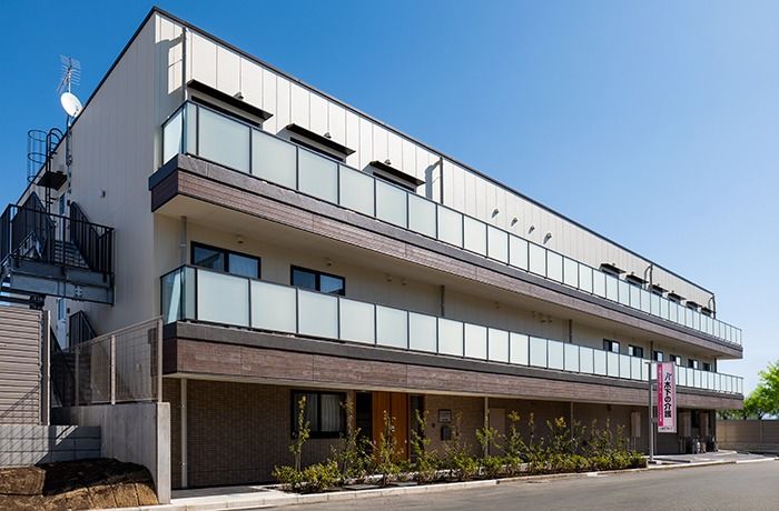 施設名が書かれた大きな看板が屋根の上に設置されている、3階建ての施設建物