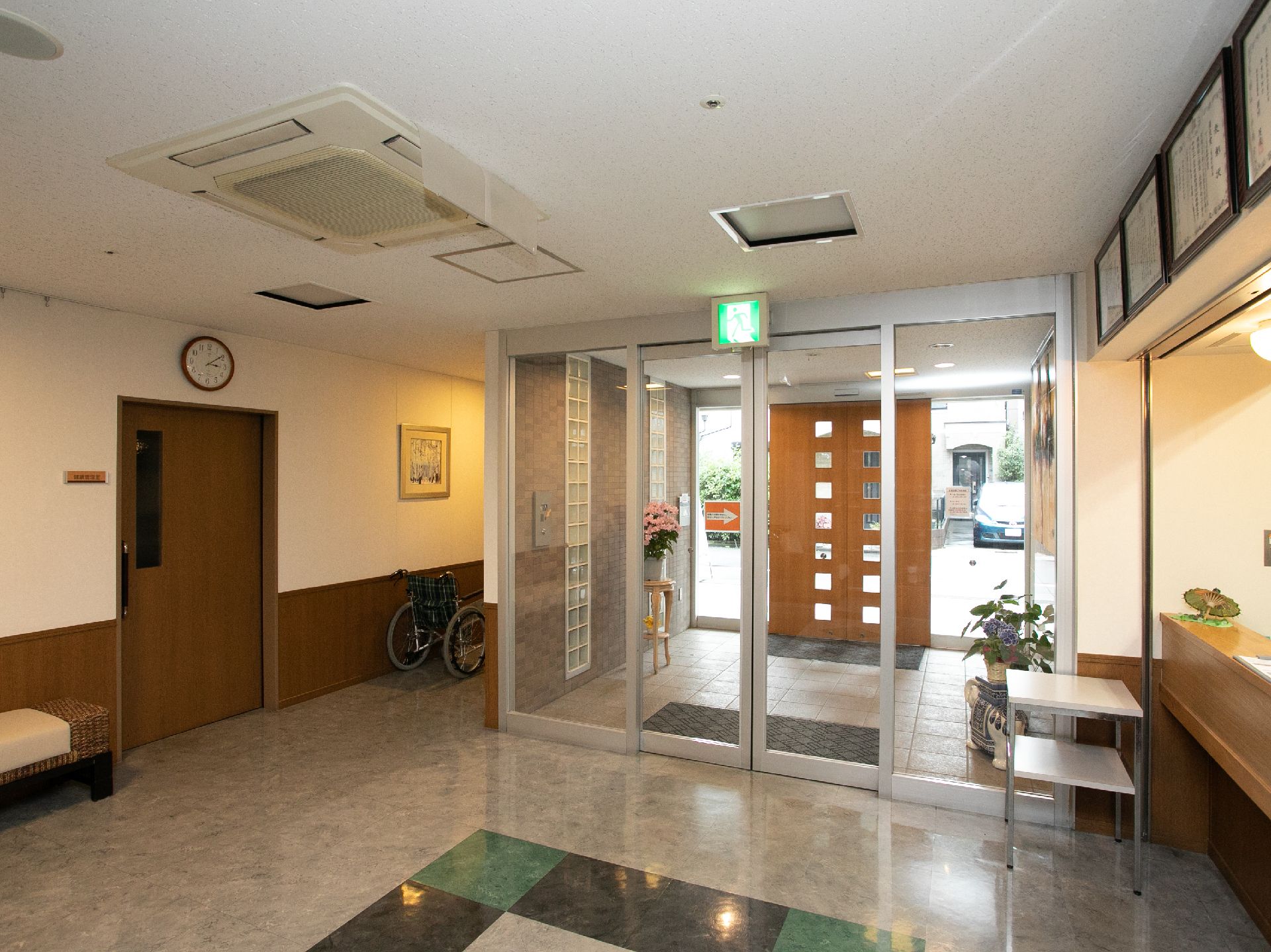 ガラスの自動ドアが設置されている施設入口にある非常口誘導灯