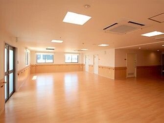 服薬をうながすスタッフとそれに従って薬を飲もうとしている女性。施設内の一場面