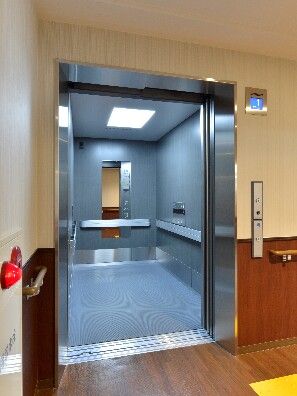 手すりや鏡が付いたストレッチャー対応のエレベーター。エレベーターホールには防火設備もある。
