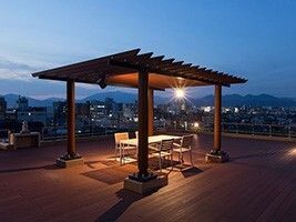 屋上テラスにある東屋の夜景。簡単な日よけとテーブル、いすなどがある様子