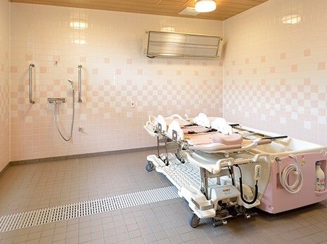 臥位浴対応型浴槽とそれが置いてある浴室の様子。エアコンがついている壁とシャワースペース
