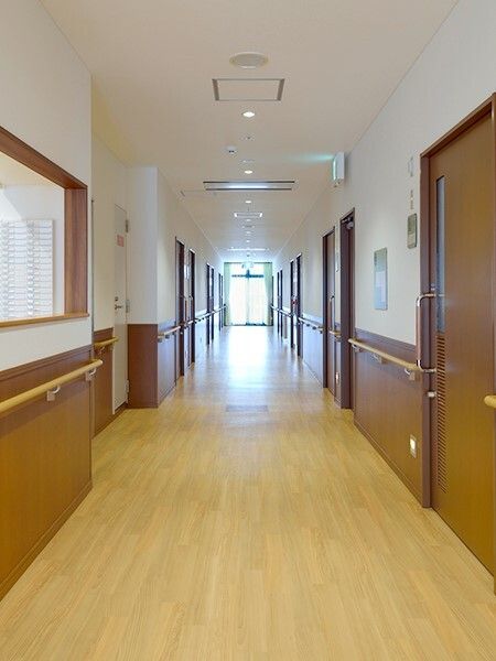 手すりがついた施設内の廊下の様子。個室のドアが写っている写真
