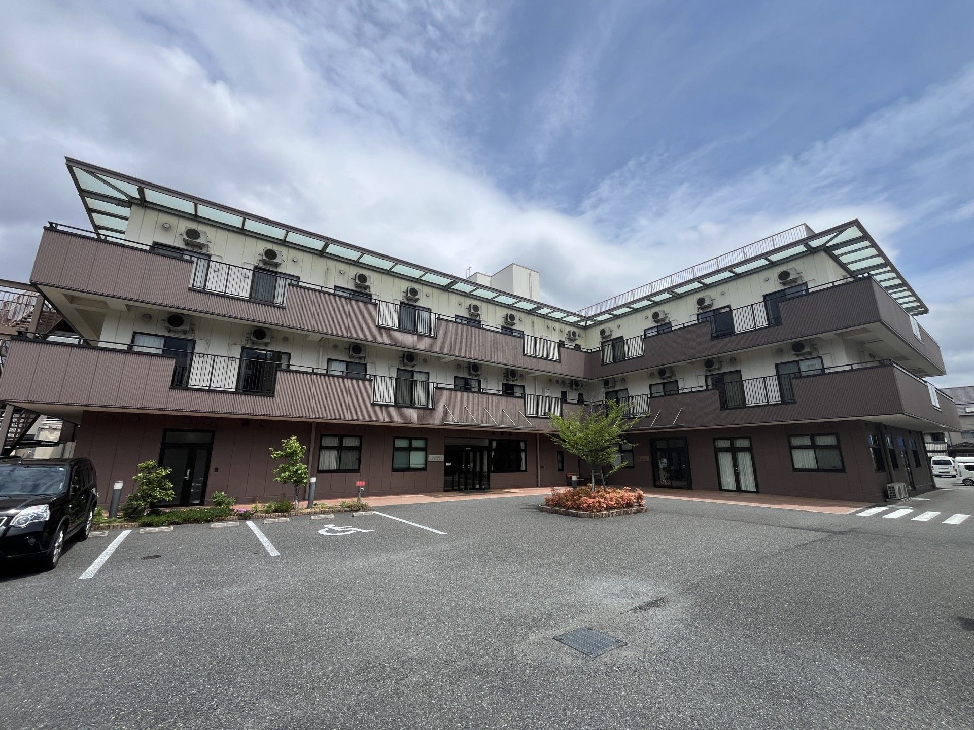 なにかを指さして笑顔で話している車いすの女性とそれを押している介護スタッフの様子