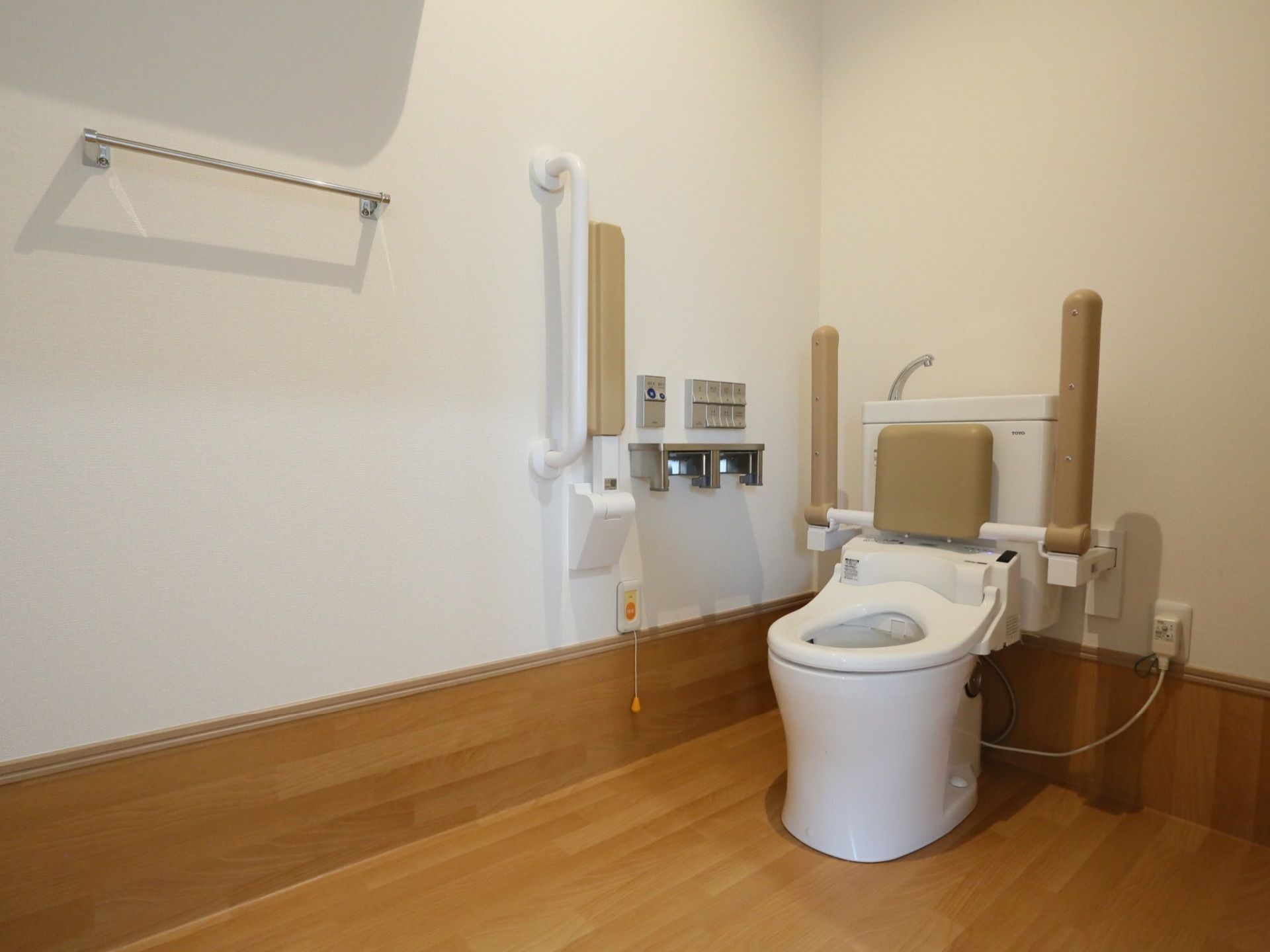 トイレの内装は、フロアから足元にかけて木目が見える素材を使用している。茶系の背もたれと肘掛けが設置してあり、操作ボタンは銀色である。