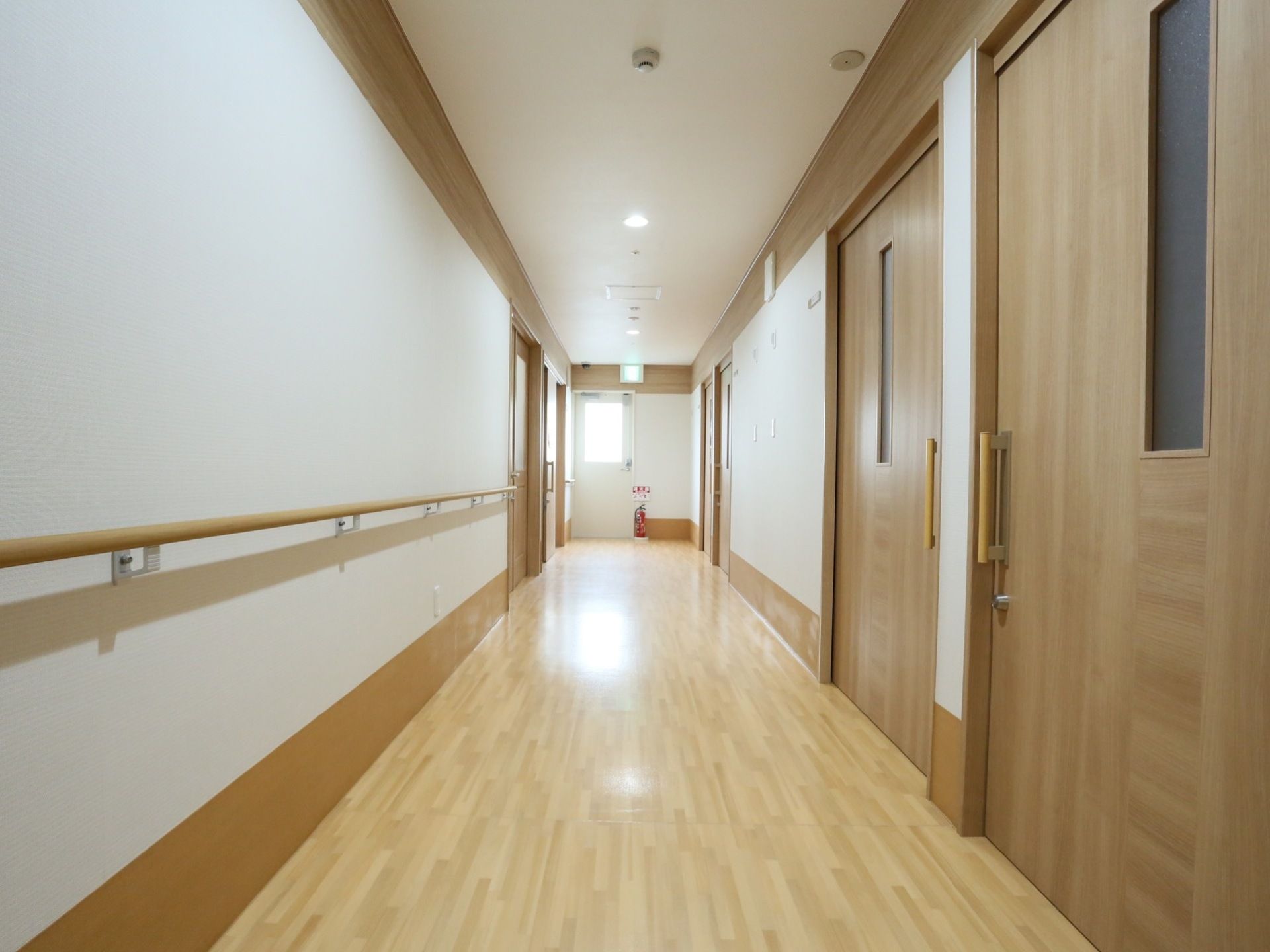 幅のある広く明るい通路。天井の照明に床がつややかに照らされており、清掃が行き届いている印象である。壁には手すりがついている。