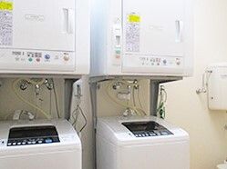 シンプルな部屋には縦型の洗濯機が2台、それぞれの洗濯機の上に四角い乾燥機が設置されている。
