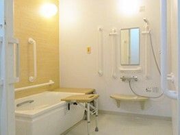 浴槽のサイドにベンチが付いた個浴室。可動式のベンチが手前にも設置され、壁には呼び出しボタンも付いている。